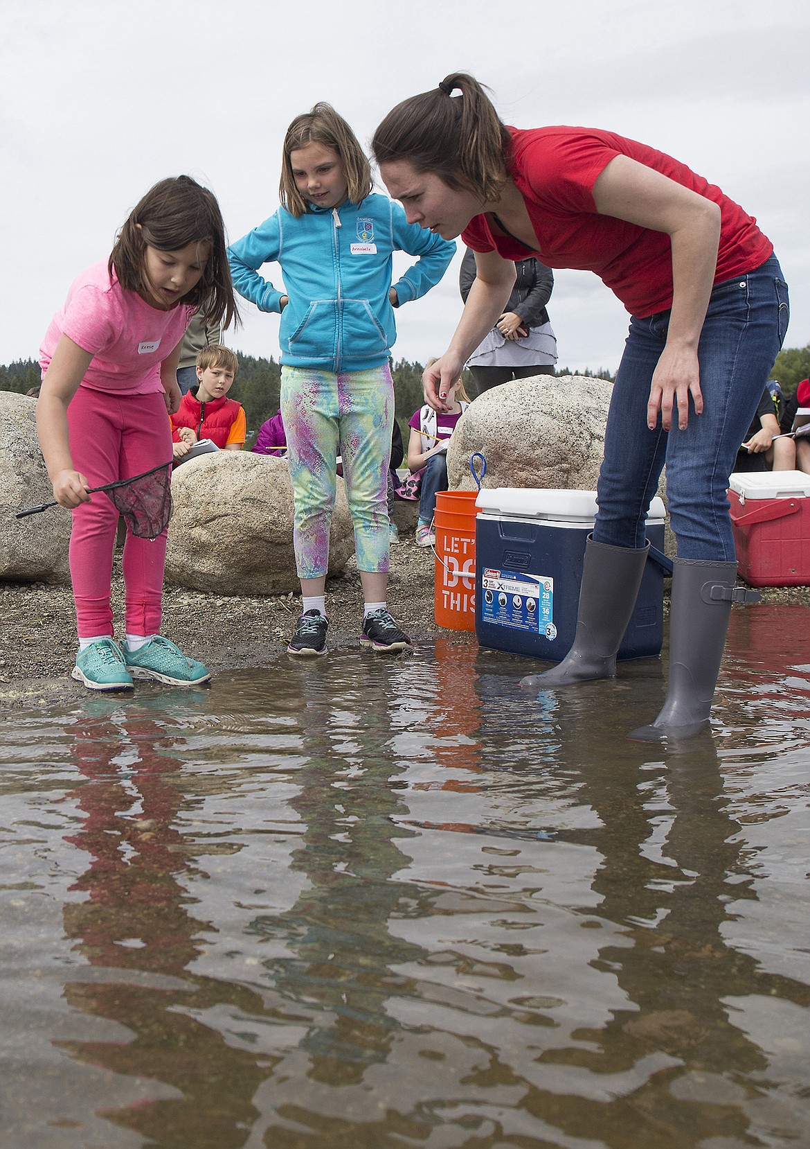 LISA JAMES/PressRamsey Magnet School of Science second-graders Reese Herrera, left, and Annabelle Louviers, get help from student teacher Julia Schatz releasing one of the rainbow trout they started raising in January into Hauser Lake on Thursday, as classmate Marek Parson watches.Volunteers from Kootenai County Sheriff's Search and Rescue also did demonstrations with the students on how to stay safe in the wilderness.