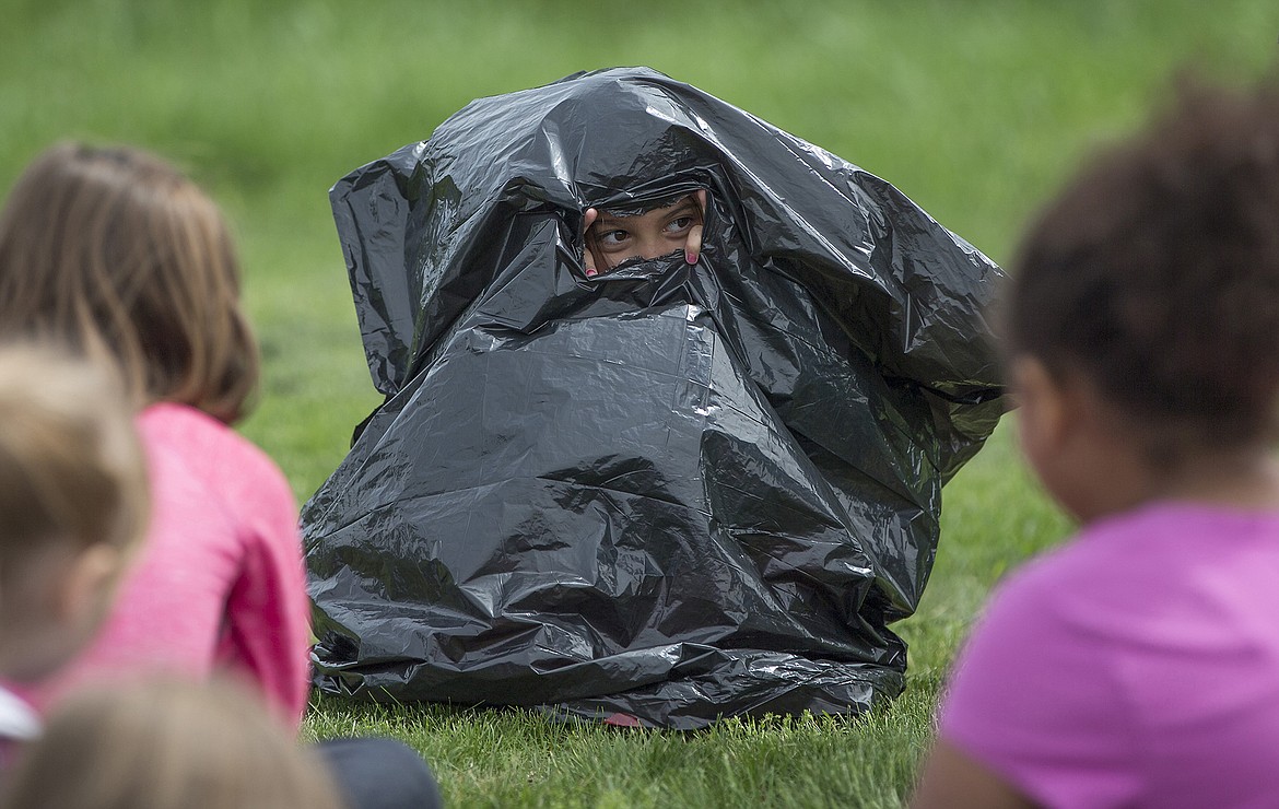 LISA JAMES/PressRamsey Magnet School of Science second-grader  Jasmine Daffer finds shelter from the rain in a Hefty bag during a demonstration by Kootenai County Sheriff's Search and Rescue volunteers at Hauser Lake on Thursday on how to stay safe in the wilderness. The students were at Hauser Lake to release the rainbow trout they started raising in January into the lake.