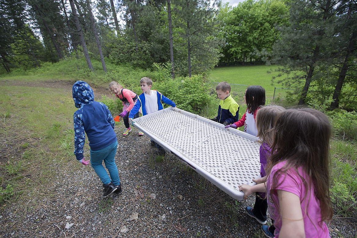 LISA JAMES/Press
John Brown Elementary School first-graders work together to carry out the top of a broken table they found during a litter cleanup near their school on Thursday, May 18.
Local environmental activist Dylan Stiegemeier, who started The Theodores, went out with students and teachers after teaching them about littering and recycling.