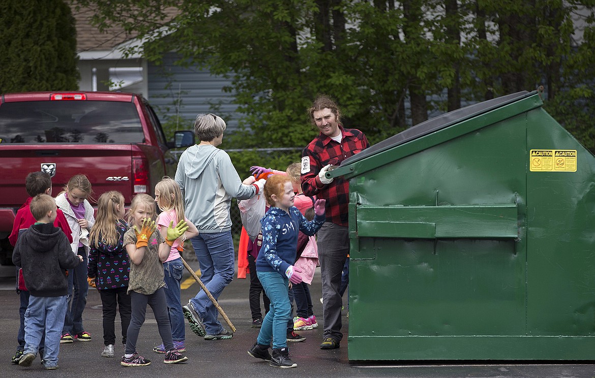 LISA JAMES/Press
Local environmental activist Dylan Stiegemeier, in red plaid, helps John Brown Elementary School first-graders put their collected trash into a dumpster after a litter cleanup in the woods near their school on Thursday, May 18.
Stiegemeier, who started The Theodores, went out with students and teachers after teaching them about littering and recycling.