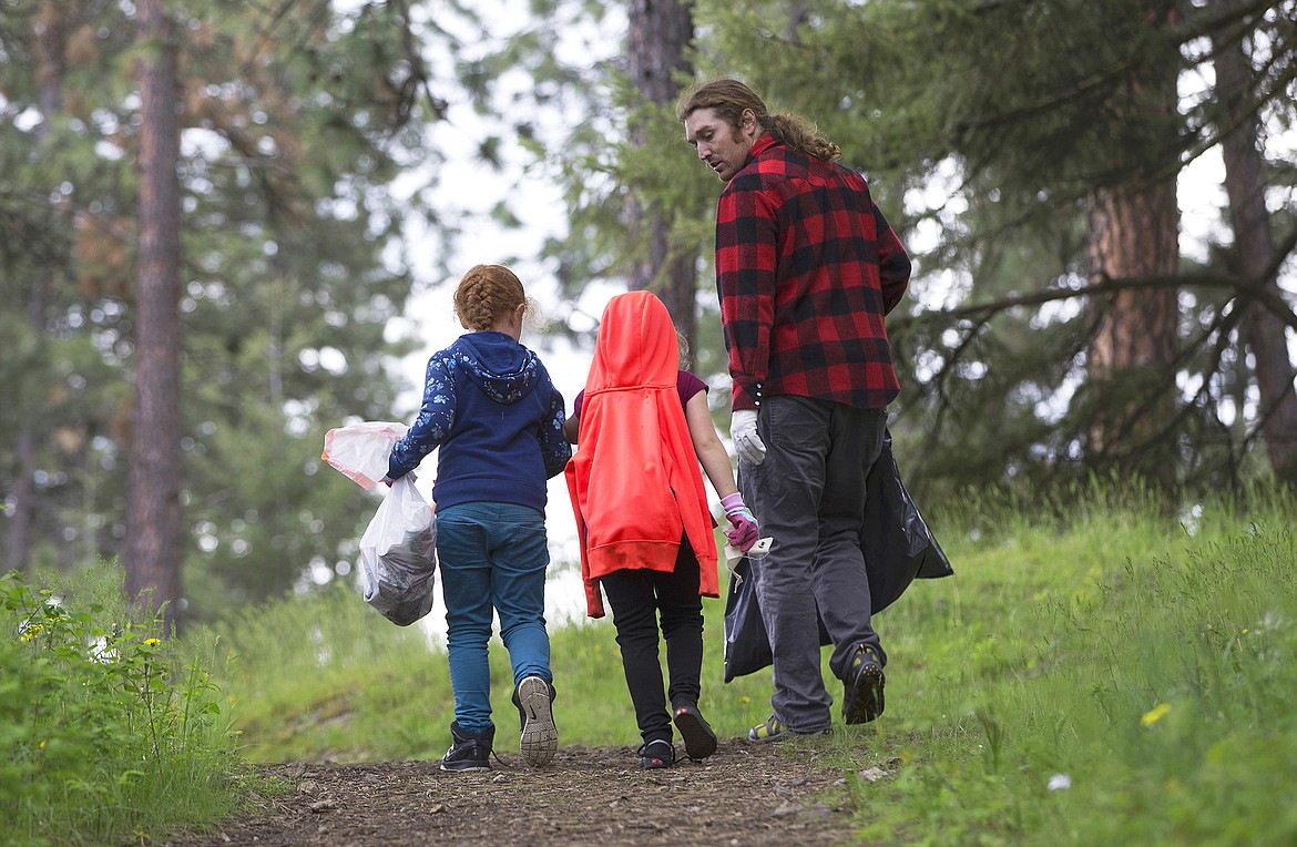 LISA JAMES/Press
Local environmental activist Dylan Stiegemeier, walks through a patch of woods collecting trash with John Brown Elementary School first-graders Hazel Nutterville, left, and Casey Slokum during a litter cleanup in the woods near their school on Thursday, May 18.
Stiegemeier started The Theodores, based on the ethos and laws passed by President Teddy Roosevelt, to teach people about littering and recycling, but also to motivate them to clean up after others.