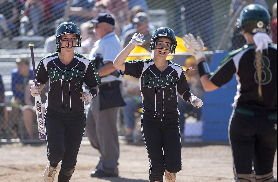 LISA JAMES/PressEagle players Delayna Waite, 5, Kate Kukla, 3, return to high-fives from Rachel Menlove, 8, and teammates in the dugout after scoring the first home runs of the final 5A State Championship game against Lake City during the 5th inning at Coeur D'Alene High School on Sunday.