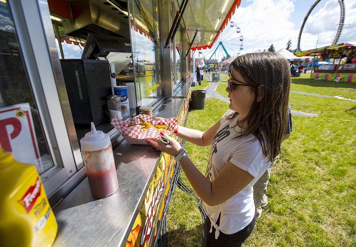 LOREN BENOIT/PressJoyce Loan purchases a basket of fries at one of the Spring Fest vendors at the Kootenai County Fairgrounds on Saturday.