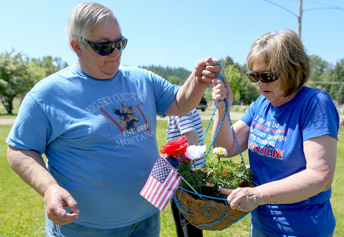 Tom Gab, left, and wife Nancy Gab of Libby prepare a hanging basket of flowers at Libby Cemetery on Memorial Day Monday, May 29, 2017. They were going to hang the arrangement aside the grave of Roland &#147;Rolly&#148; Childs. (John Blodgett/The Western News)
