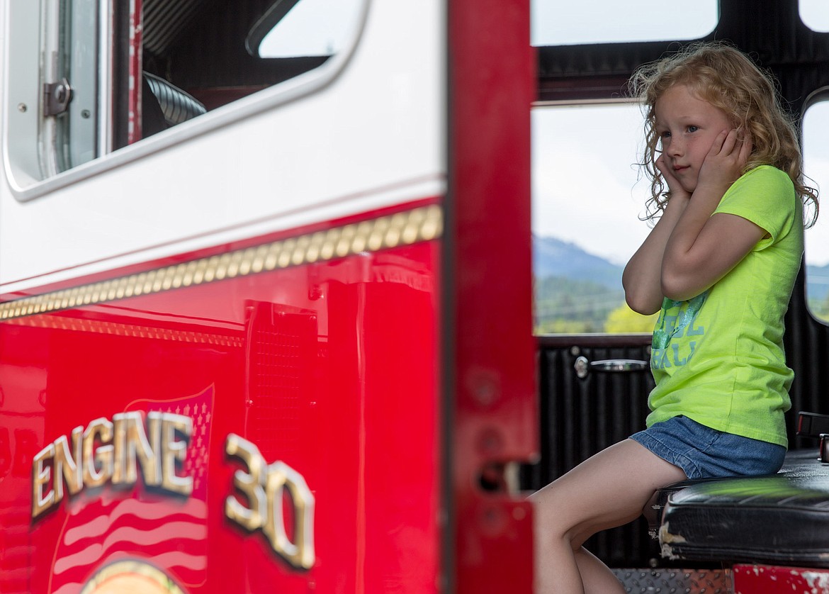 Harmony Keller, 6, of Libby covers her ears in anticipation of the siren while sitting in Libby Volunteer Fire Department&#146;s Engine 30 at Fireman&#146;s Park Saturday.
