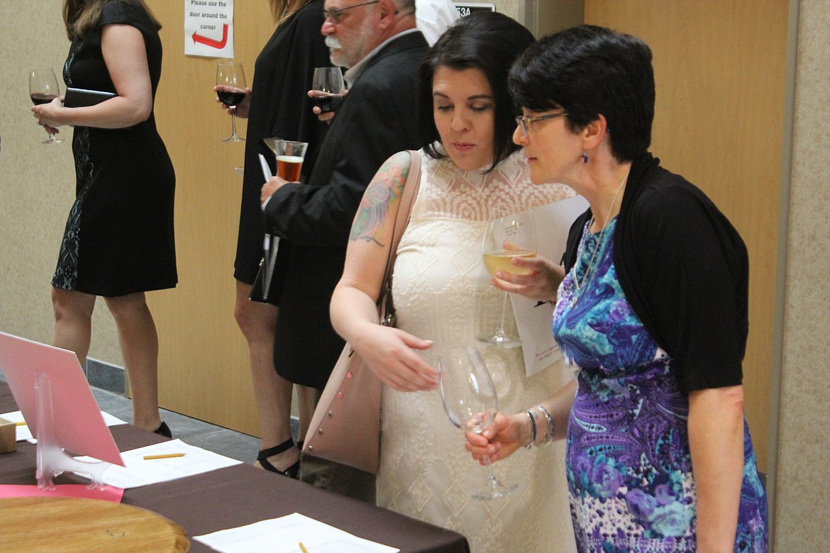 Richard Byrd/Columbia Basin Herald
Most attendees at Saturday night&#146;s Cellarbration checked out the items up for bid in the silent auction with a glass a wine in their hand.