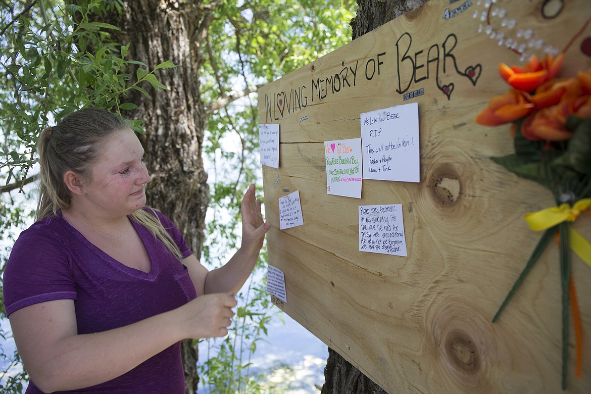 LISA JAMES/PressMissy Holbrook posts a note on a memorial sign for her dog, Bear, at Hayden Lake Tuesday. The sign was hung earlier in the day at the spot along Hayden Lake Road  where Bear drowned after being pulled down against a drainage grate on Monday.