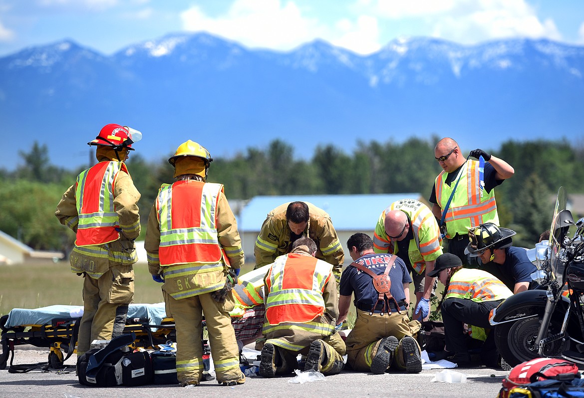 First responders from South Kalispell Volunteer Fire, Kalpsell Fire and Evergreen Fire and Rescue, work to help a victim of a motorcycle accident on Tuesday, May 30 at the intersection of Lower Valley Road and Willow Glen Drive. Two persons were injured and transported to the hospital.(Brenda Ahearn/Daily Inter Lake)