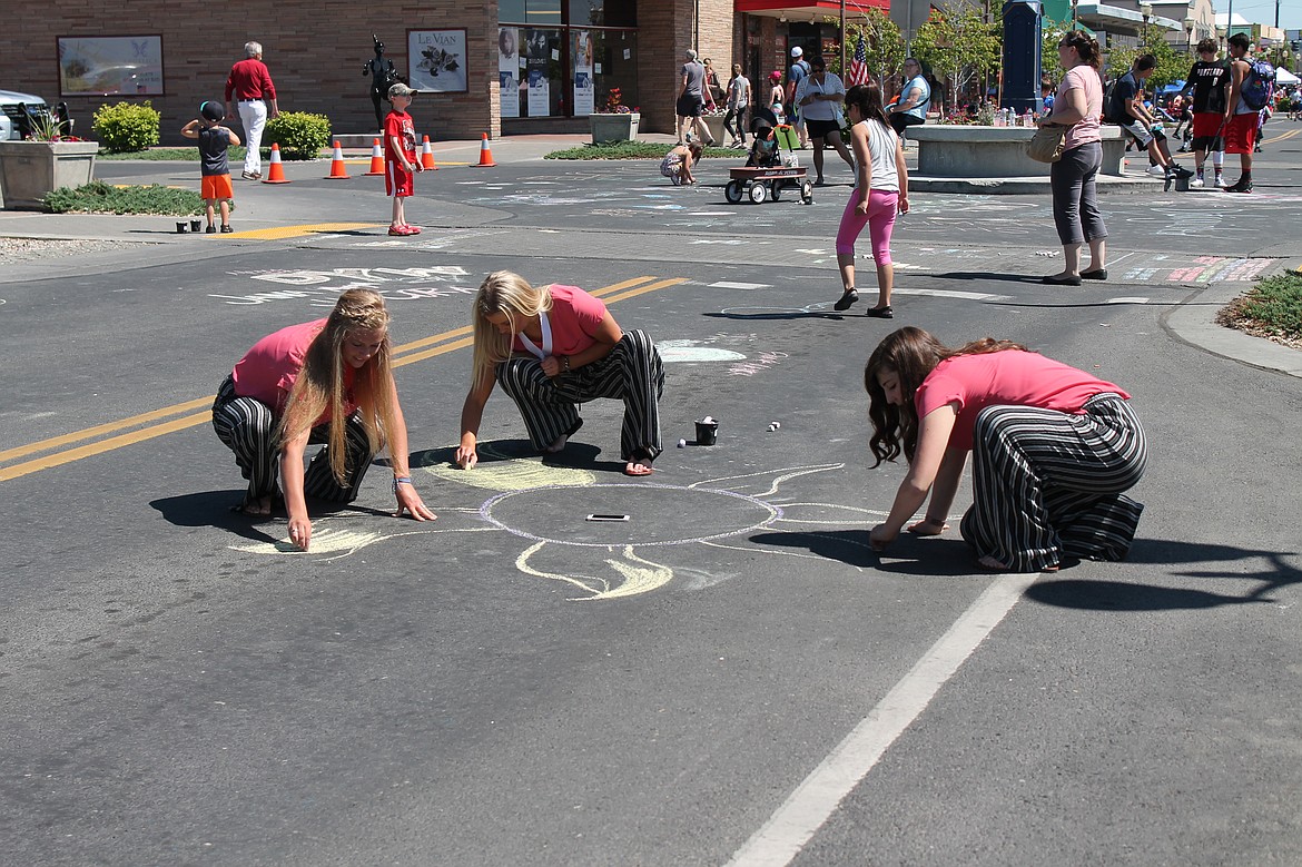 Charles H. Featherstone/Columbia Basin Herald
Cora Bruneel, Jana Osborne, and Morgan Tolley &#8211; all winners of the Distinguished Young Woman of Moses Lake award &#8211; draw a giant flower with chalk in the middle of Third Avenue on Saturday.