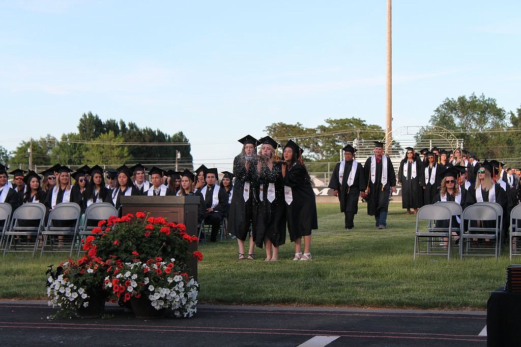 Charles H. Featherstone/Columbia Basin Herald - Three graduating seniors blow glitter at the audience during the Ephrata High School graduation ceremony on Friday.