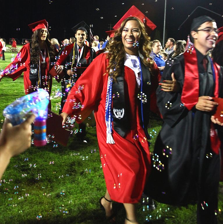 Rodney Harwood/Columbia Basin Herald - 2017 Othello High School graduates leave the stadium through a shower of bubbles provided by one of the friends and family after Friday night's ceremonies at Huskie Stadium.