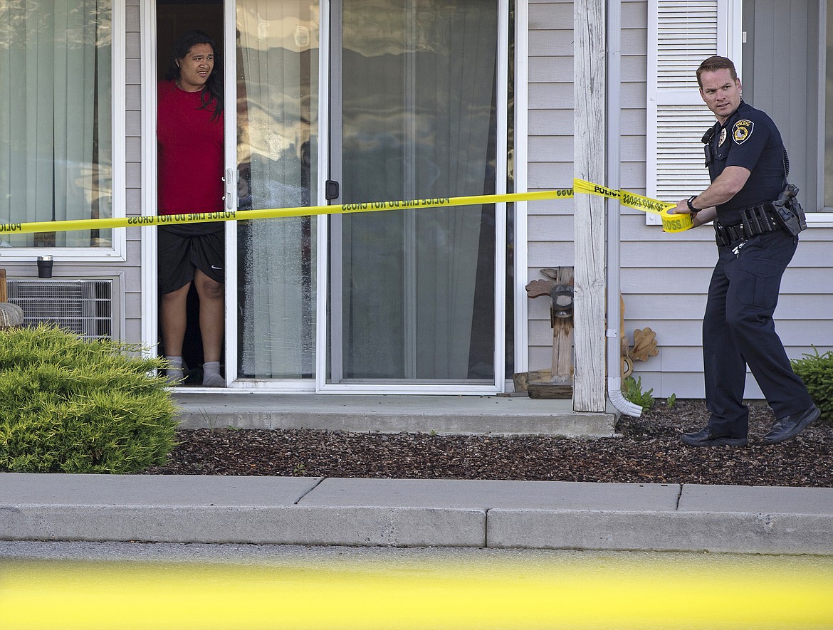 LISA JAMES/Press
A neighbor watches as Coeur d&#146;Alene police officer Caleb Hutchison tapes off an area in the Falls Creek Apartments complex in Coeur d&#146;Alene where two bodies were found on Thursday.