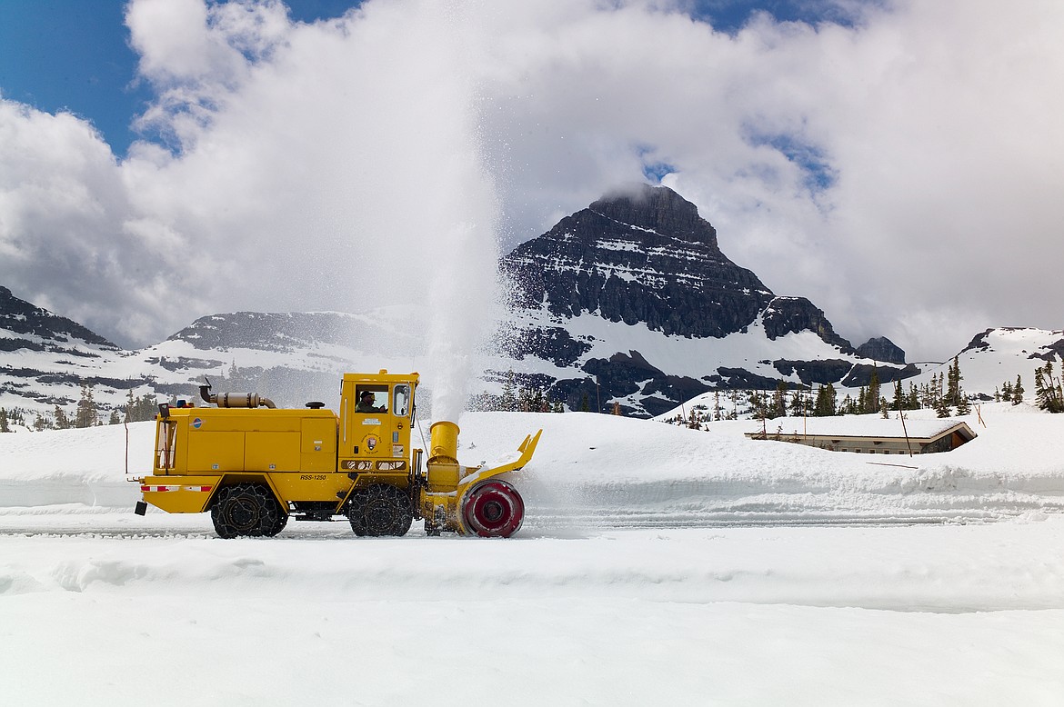 A Glacier Park rotary plow clears the Logan Pass parking lot Friday morning. Behind it the pit toilet is still under snow. The peak in the background is Mount Reynolds. (Chris Peterson photo)