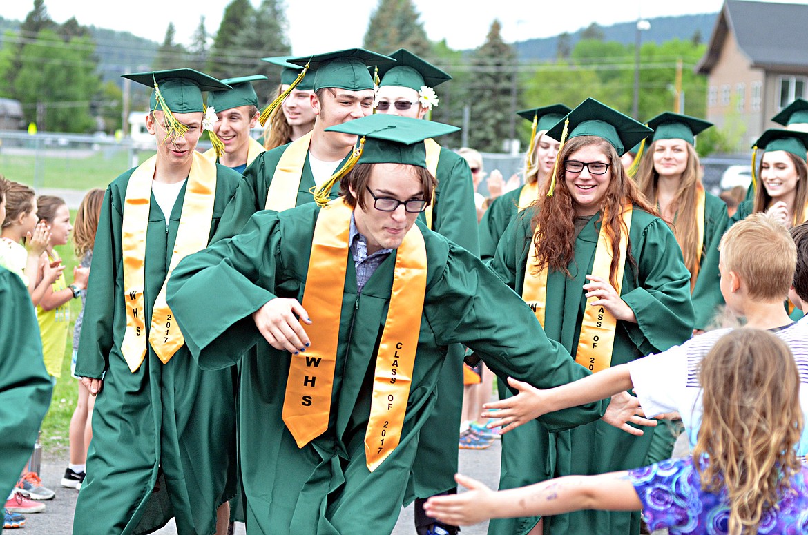 Solomon Ziegert, followed by Savannah Krause, gives high fives to students Friday outside Muldown Elementary School. Graduates from the Class of 2017 walked through Muldown and Whitefish Middle School to rounds of applause. The high school hopes to make the event an annual tradition. (Heidi Desch photos/Whitefish Pilot)