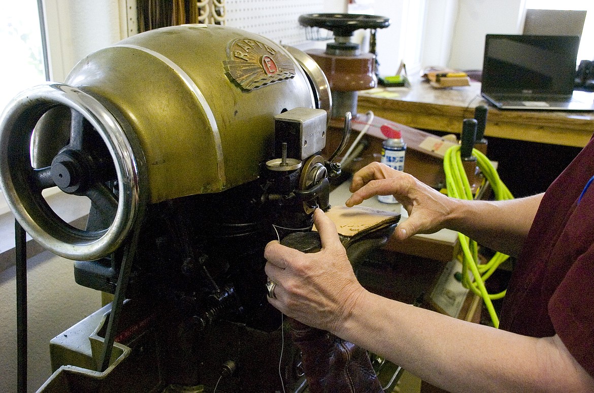 DALE LANE sews on a new sole at his boot and shoe repair store in Polson last week. Lane said the heavy-duty sewing machine can easily drive a needle through a human finger. (Brett Berntsen/Lake County Leader)