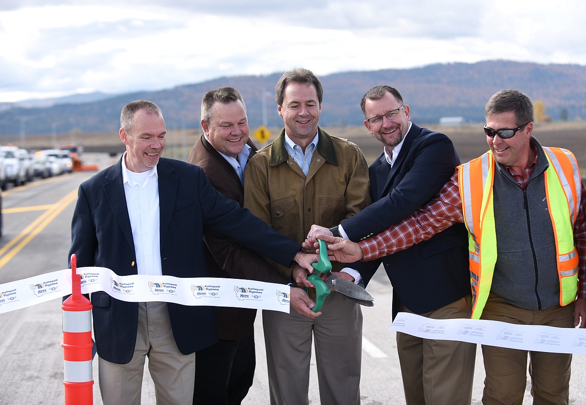 Montana Department of Transportation Director Mike Tooley, from left, U.S. Senator Jon Tester, Montana Governor Steve Bullock, Kalispell Mayor Mark Johnson and MDT project manager Jim Mitchell cut a ribbon at the bridge over Reserve Loop Drive on the U.S. 93 Alternative Route on Friday. (Aaric Bryan/Daily Inter Lake)