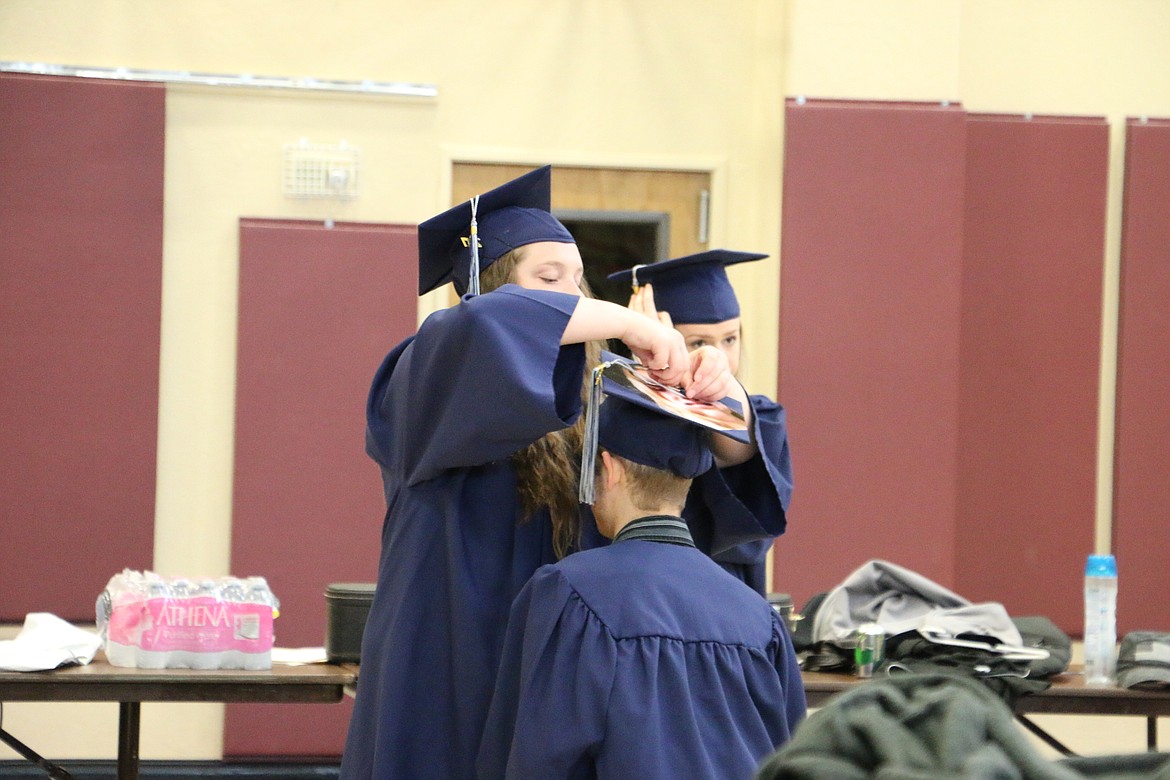 (Photo by MARY MALONE)
Forrest Bird Charter School graduate Miranda Paddack fixes classmate Alexander Riach's tassle before Saturday's graduation ceremony.