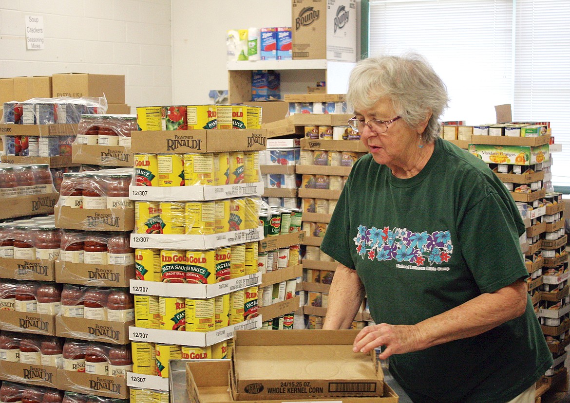 Volunteer Chloe Adamson is surrounded by towers of cans in Libby Food Pantry’s canned goods room, one of four rooms being used by the food pantry in Asa Wood school. (Elka Wood/The Western News)