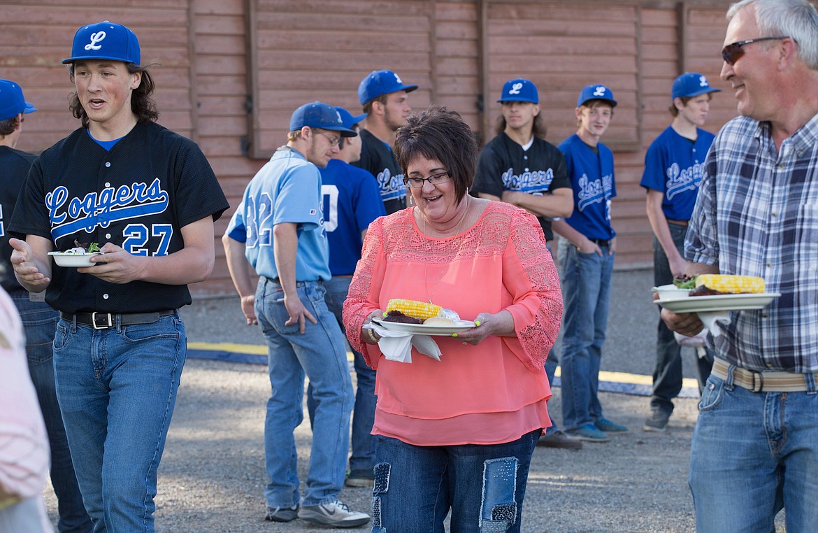 Libby Logger player Shayne Walker carries Renee Schad&#146;s salad as she and her husband Al Schad go to their seats at Dinner on the Diamond at Lee Gehring Field in Libby Friday, June 9, 2017.