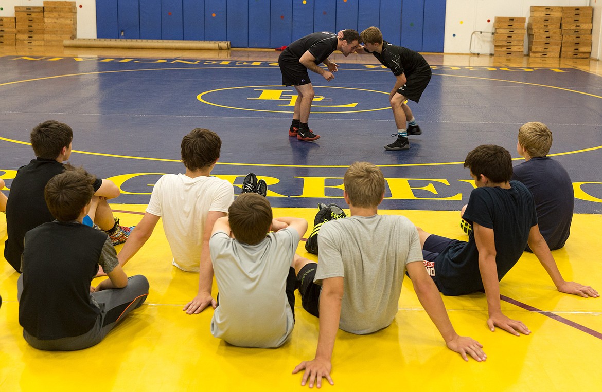 Stanford University wrestling coach Jason Borrelli, left background, and Libby High School junior Buddy Doolin demonstrate wrestling moves during the second day of the Greenchain Wrestling Camp Sunday, June 11, 2017.
