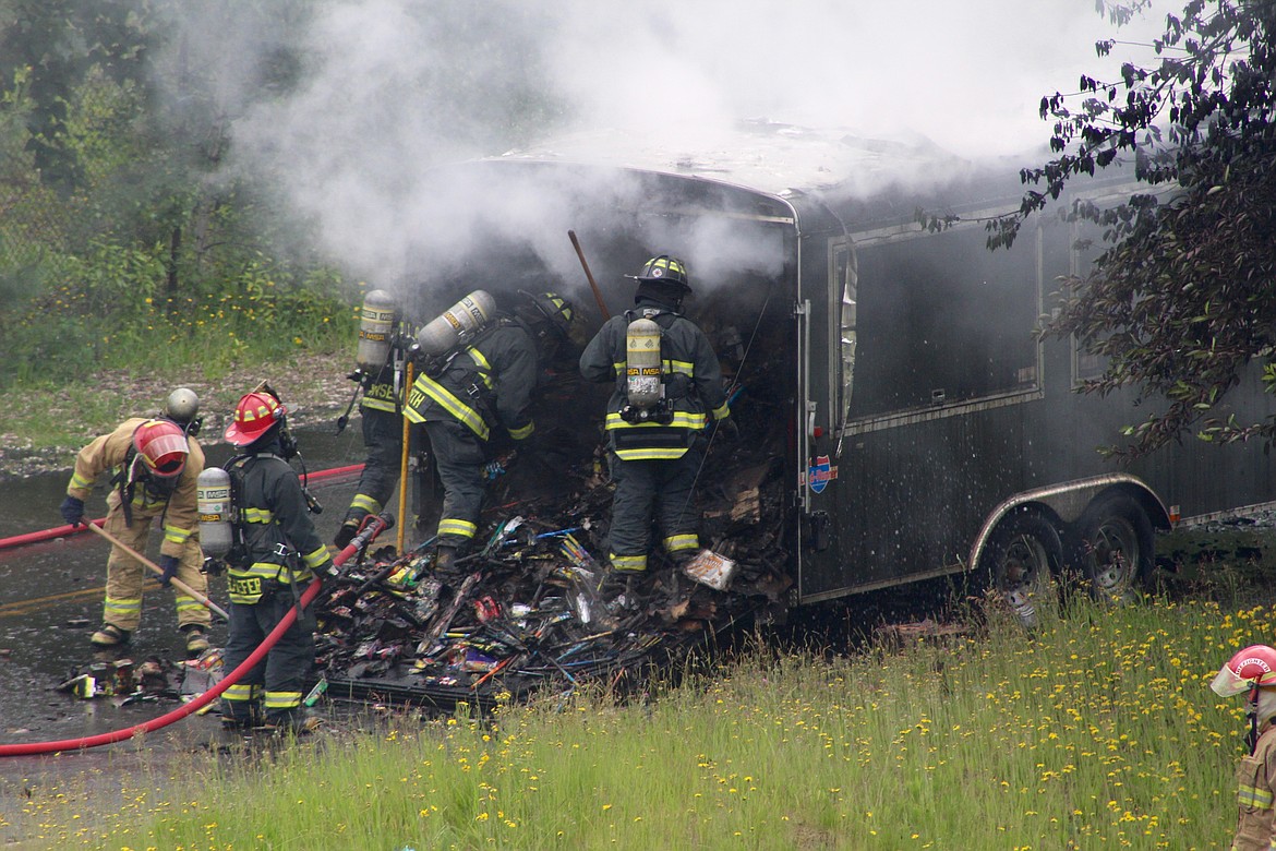 Fire crews work to loosen the massive amount of fireworks out of the trailer.