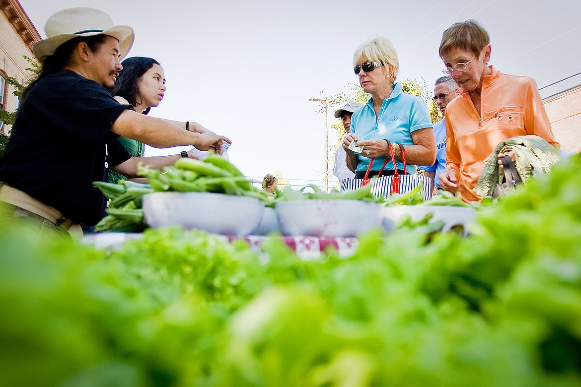 SHAWN GUST/Press file
Wachu Cho, far left, and stepdaughter Sandy Glenn package some fresh yellow beans, grown in their local garden, for Sharron Lewis and her sister, Berne Newfeld, far right, in July 2015 at the Farmers Market in downtown Coeur d&#146;Alene. In addition to buying local produce, shoppers at the Wednesday market will now be able to sip wine samples offered by local vendors.