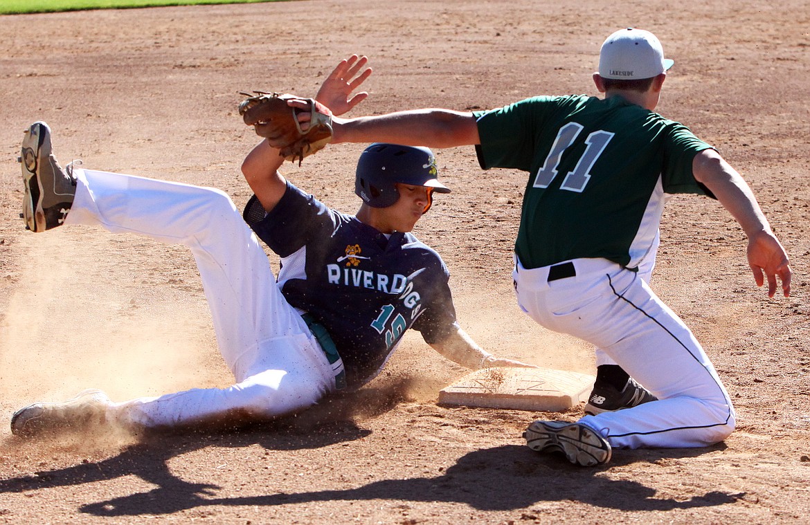 Rodney Harwood/Ciolumbia Basin HeraldRiver Dogs runner Arcenio Martinez (15) slides safely under the tag of Lakeside Recover third baseman Trevor Dahl (11) during Friday's game at the High Desert Baseball Classic at Johnson-O'Brien Stadium in Ephrata.