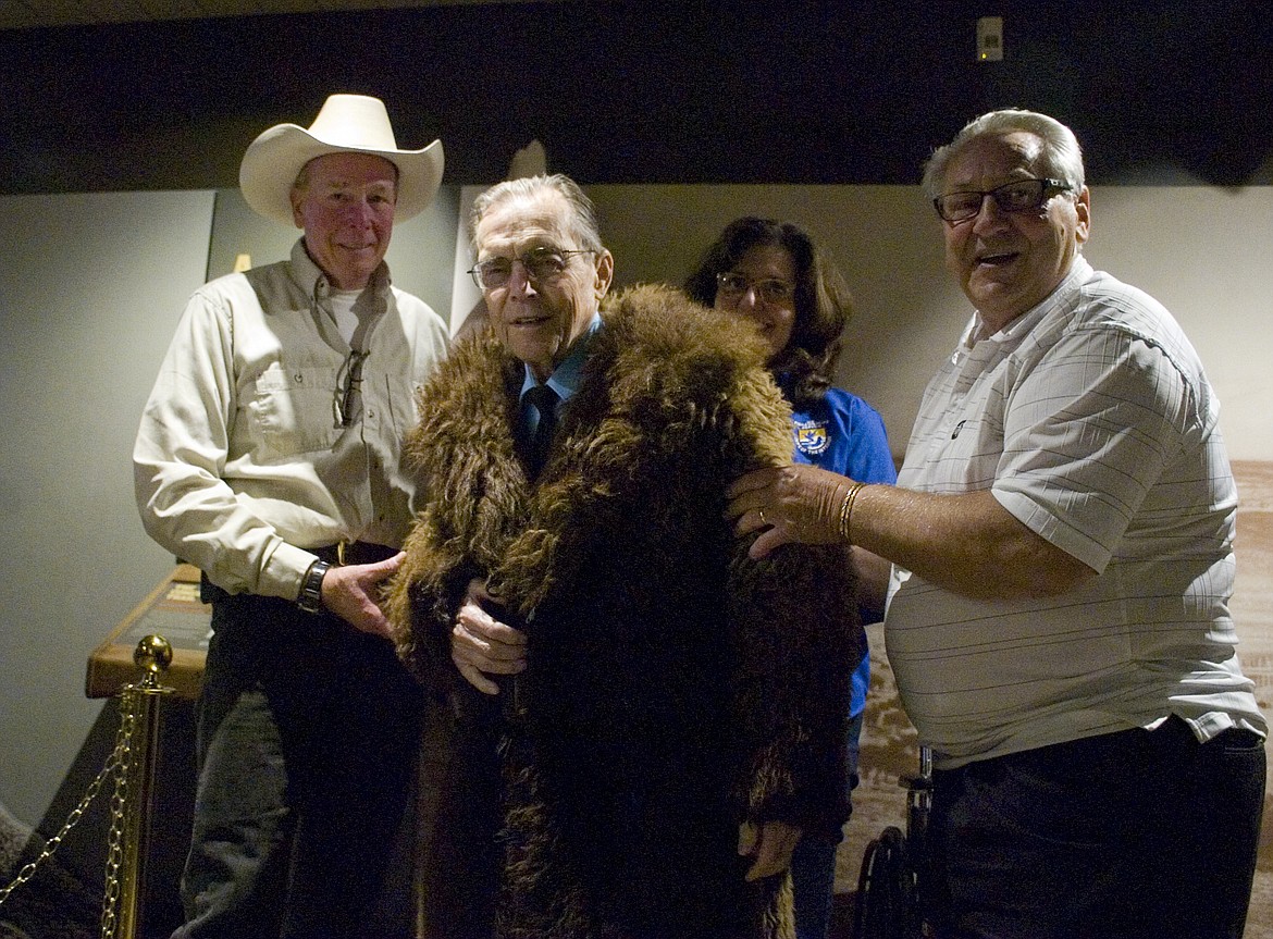 Courtney Gimbel, center, wears the buffalo fur coat he donated to the National Bison Range with help from Jeff King, left, and Harold Kindopp, right. (Brett Berntsen/Lake County Leader)