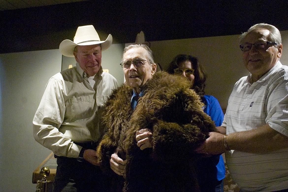 Courtney Gimbel, center, wears the buffalo fur coat he donated to the National Bison Range with help from Jeff King, left, and Harold Kindopp, right. (Brett Berntsen/Lake County Leader)