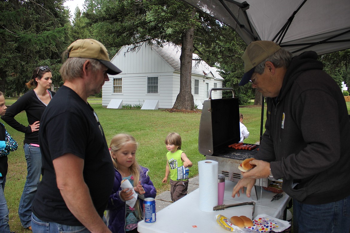 Friends of Savenac volunteer, Robert Webb serve Cam and Ben Thompson from St. Regis, a hot dog during FWP Kids Fishing Day at Savenac Pond. (Kathleen Woodford/Mineral Independent).