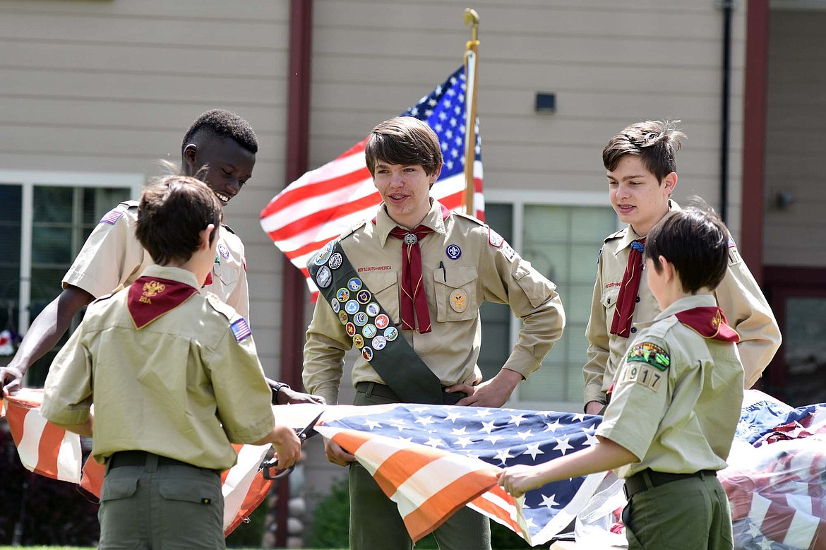 Christian Klepper (facing away), Marvin Kimera, Travis Wirtala, Jarrett Thompson and Devin Carper (facing away) work together to cut a flag into pieces to prepare it to be burned in the fire. U.S. flags must be cut before being place in the fire because when it is cut into pieces it is no longer considered a flag and then can be retired by being burned. (Heidi Desch/Whitefish Pilot)