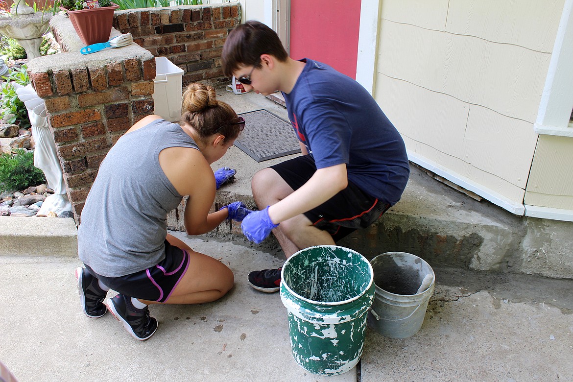 (left) Laura Mages and Matthew Carpenter work on suring up the home&#146;s foundation by applying morter to cracked areas.