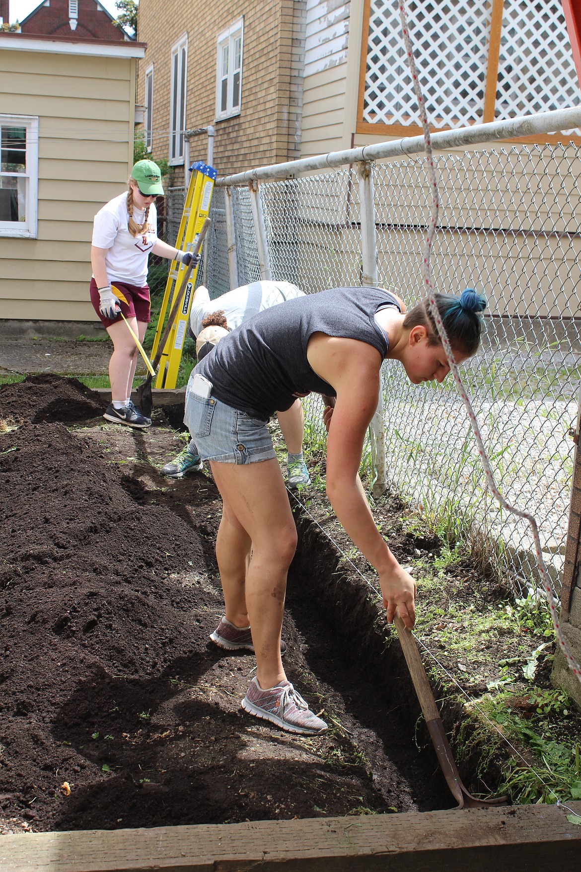 (front to back) Renee Roeber, Andrea Stakson, and Autumn Schuldt work on digging a trench that will solve a snow removal problem for Dawn in the winter.