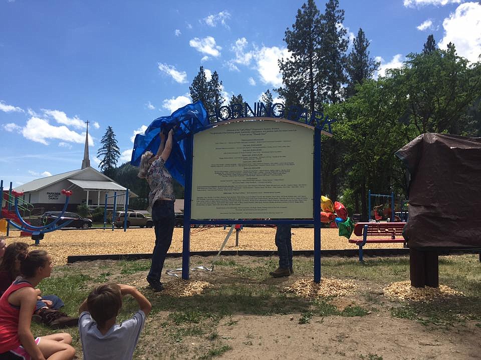 Mineral County Community Foundation member, Liz Gupton, helps to unveil one of the new signs in the Eva Horning Park in Superior. (Photo courtesy of the Mineral County Community Foundation).