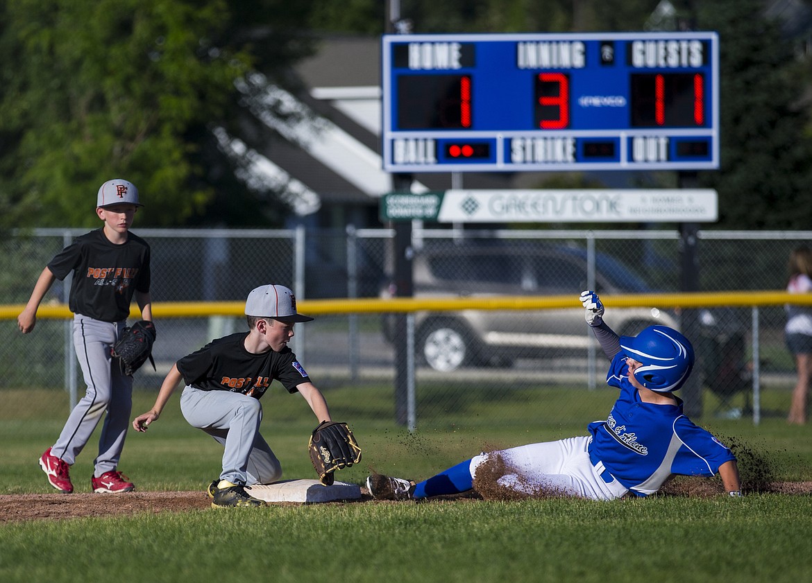 LOREN BENOIT/Press
Coeur d&#146;Alene&#146;s Andrew Karns slides safely ahead of the tag of Post Falls shortstop Steven Anderson during a Little League District 1 Majors tournament game at Canfield Middle School.