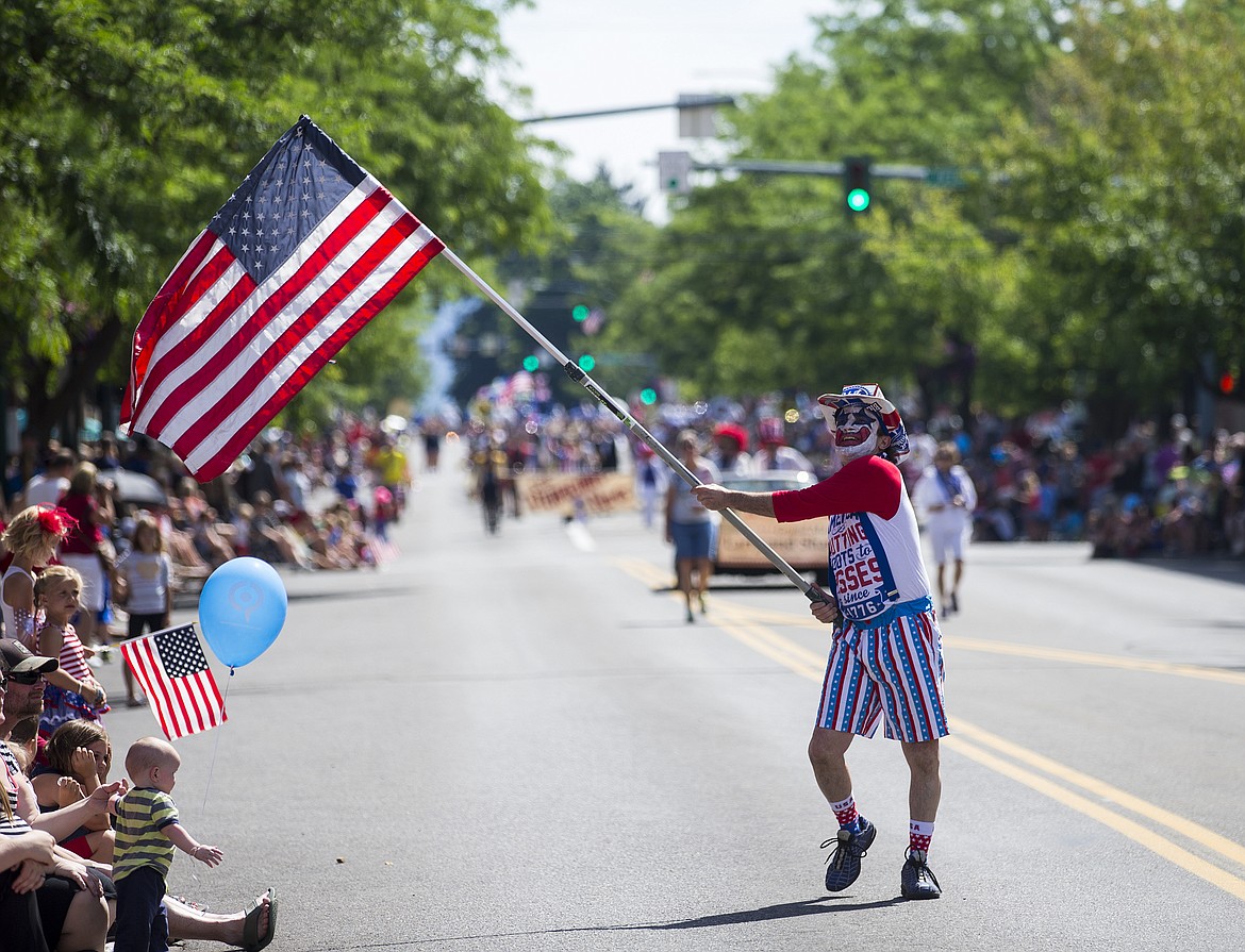 LOREN BENOIT/PressMickey Metcalf waves an American Flag as he walks down the parade route.