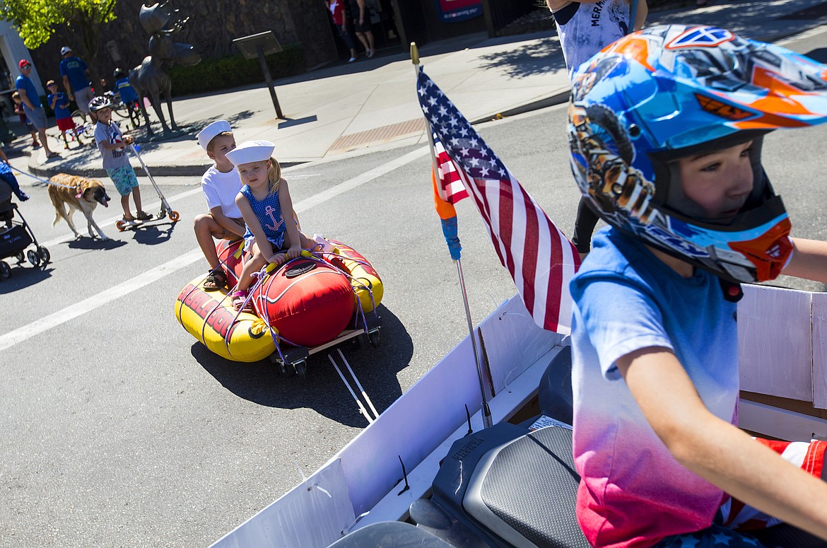 LOREN BENOIT/PressParker Chafin, 8, pulls Blake, 6, and Kylie Anderson, 3, in their double dog float during the July Kiddie Parade on Monday in downtown Coeur d'Alene.