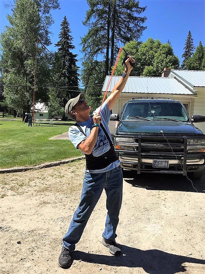 Tom Edgar uses a slingshot, ?shing line and a weight to get the lead line for his antenna high up in a tree.