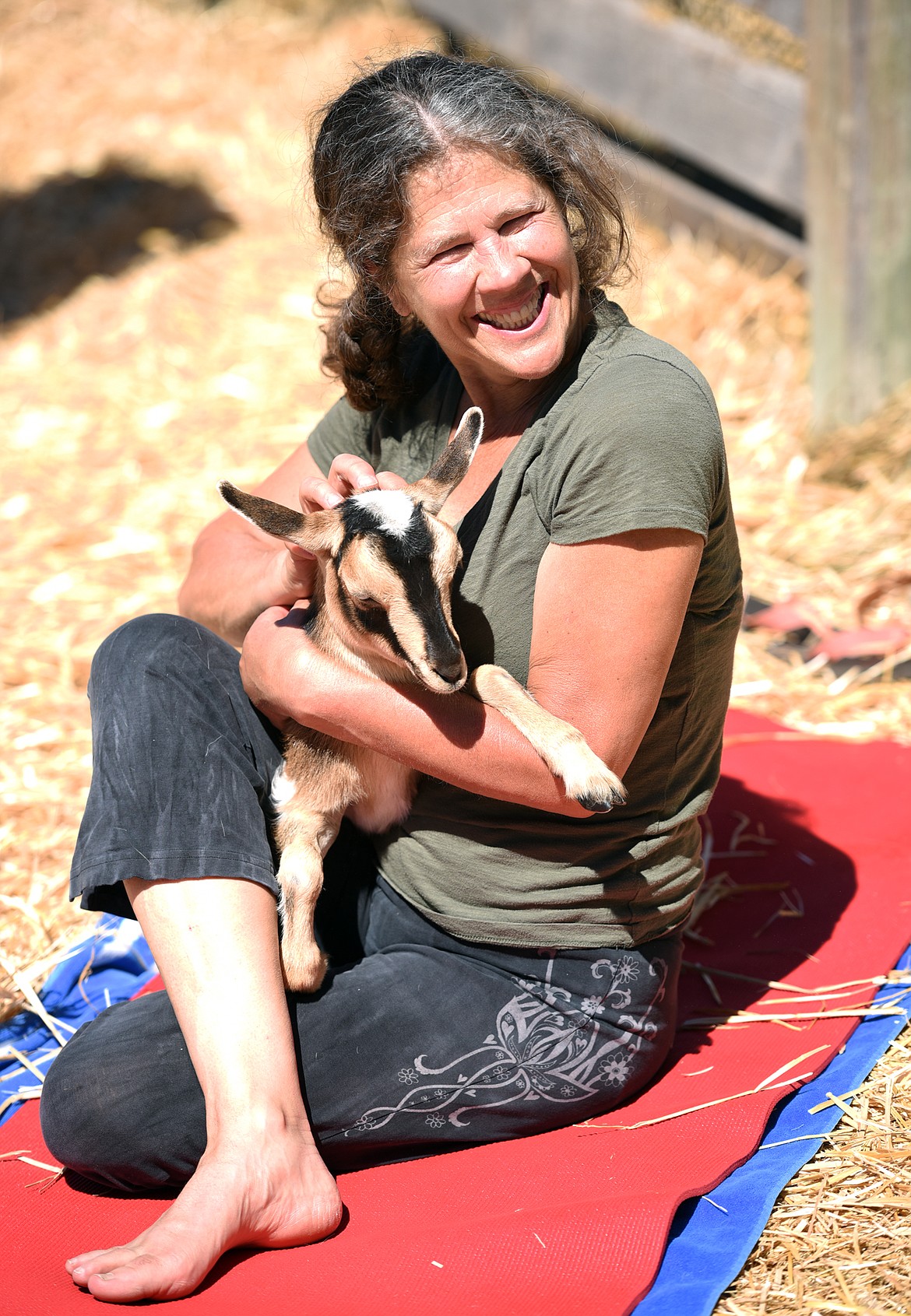 Wendy Anderson of Bigfork smiles as she holds a baby goat during Goat Yoga on Sunday, June 25, at Flying Pig Farms north of Kalispell.(Brenda Ahearn/Daily Inter Lake)