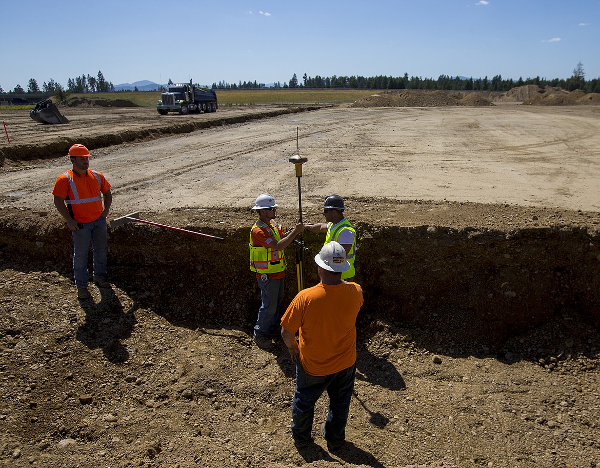 LOREN BENOIT/PressCompass Construction employees use a GPS system to measure the ground at the site of the future Super 1 Foods grocery store in Athol.