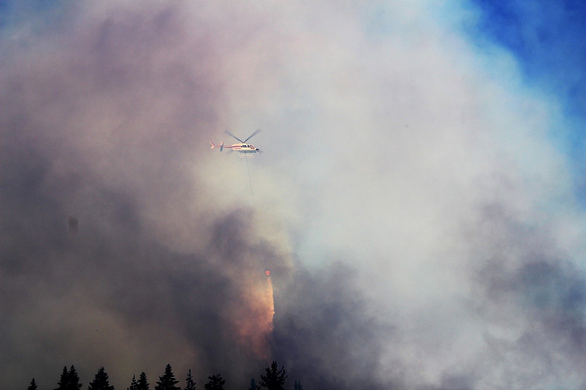 One of the three fire suppression helicopters combating the blaze releases his bucket of water.