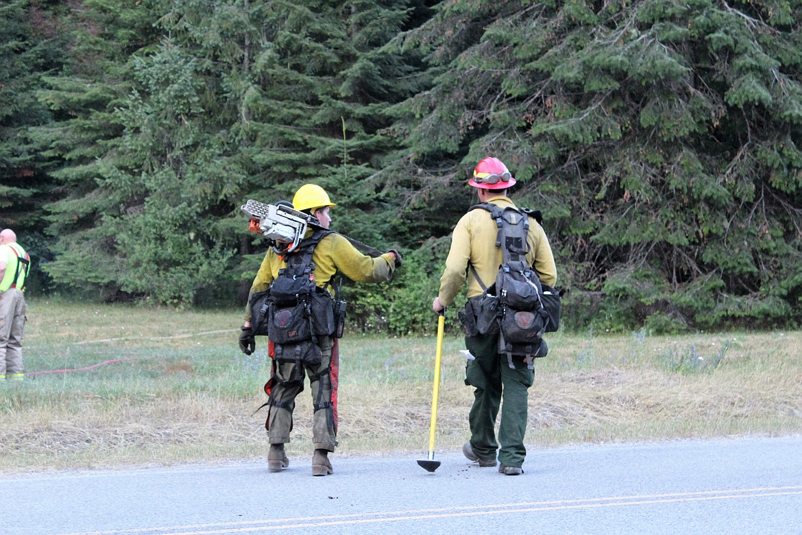Babin (red helmet) confers with one of the USFS firefighters. Crews are using chainsaws to remove unspent fuels in the operating area.
