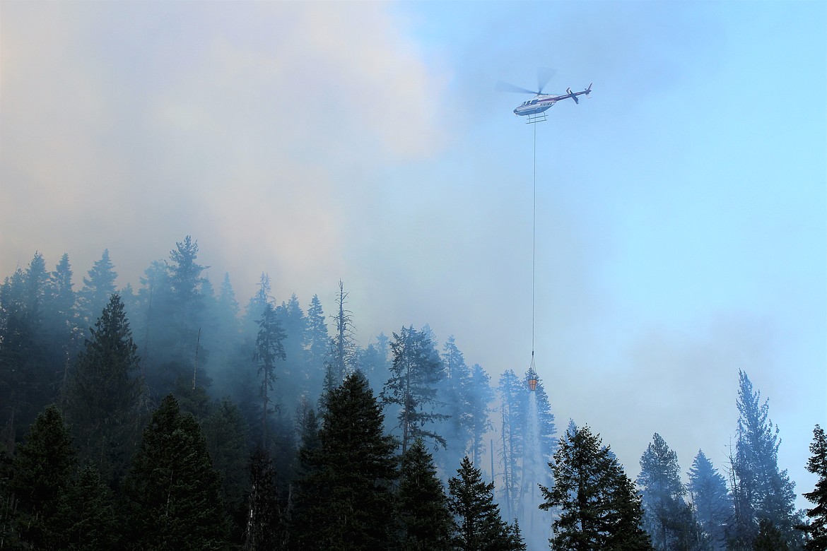 Attacking from the west side, another helicopter releases a delivery of water on the fire.