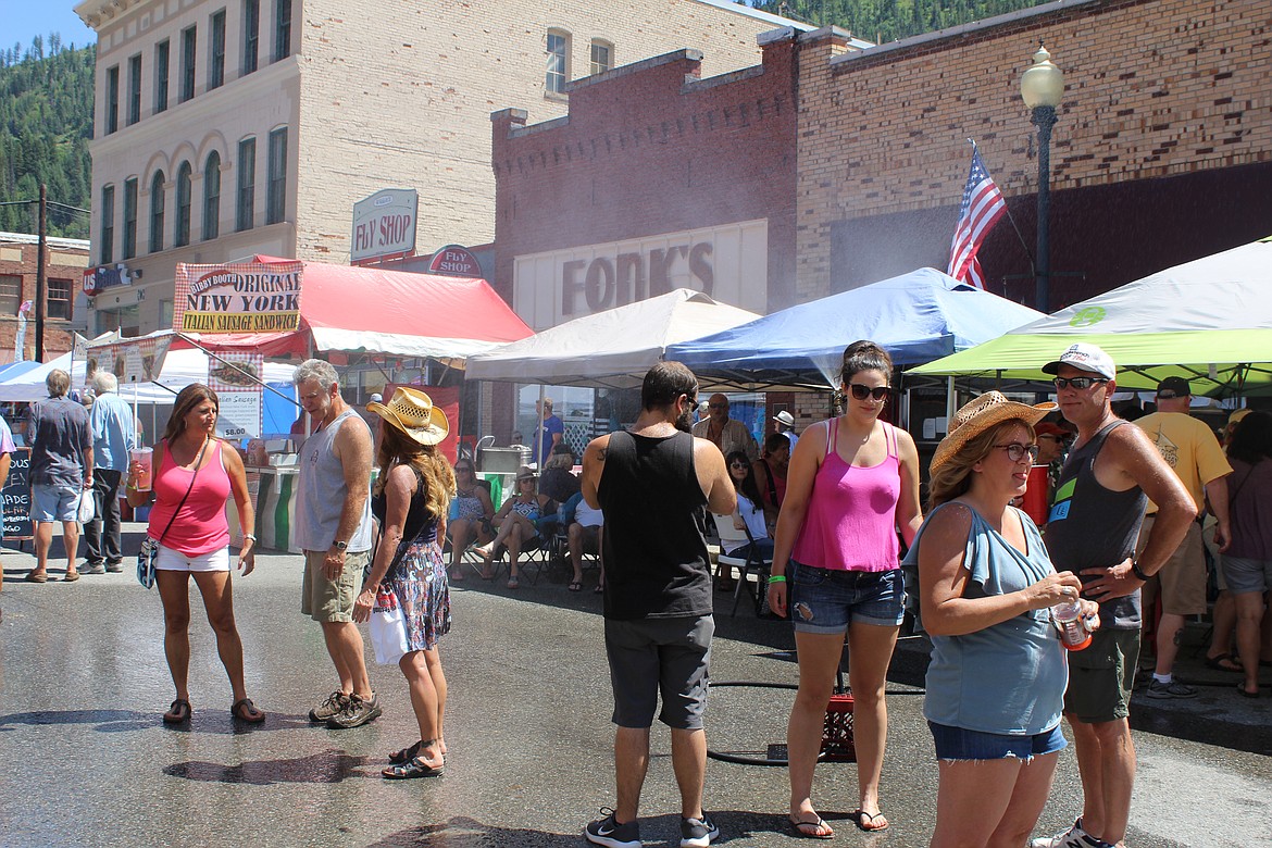 Festival goers stay cool in front of the The Metals Bar by catching some mist.