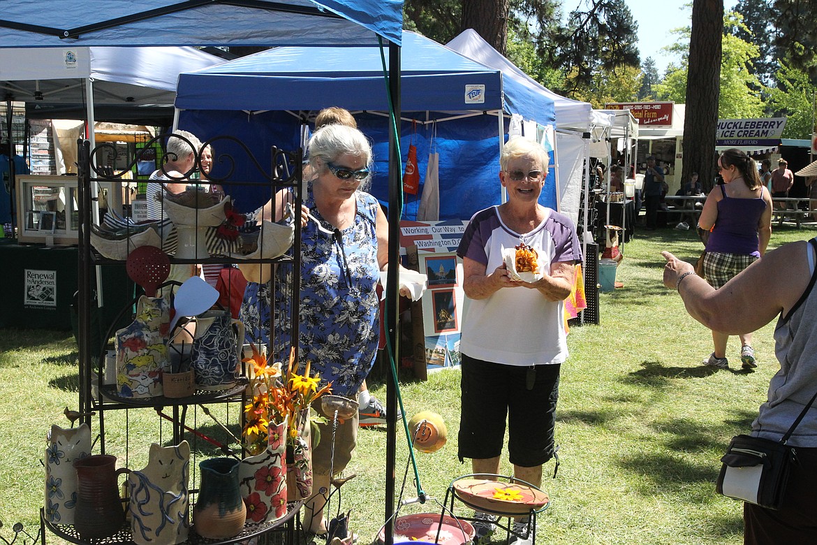 MITCHELL BONDS/Press
Toni Black, right, holds some fair food while helping her friend Sheri Cole run her handmade pottery booth. &#147;The food&#146;s been great,&#148; Black said of her favorite part of the fair.