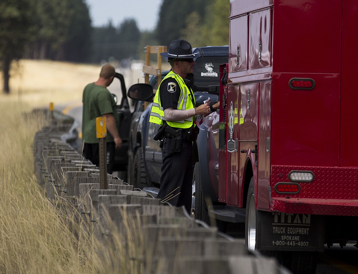 LOREN BENOIT/PressAn Idaho State Trooper speaks to a driver involved in a multiple vehicle collision on Interstate 90 near the Atlas Road overpass Thursday morning. Westbound traffic was reduced to one lane for multiple hours. No injuries were reported.