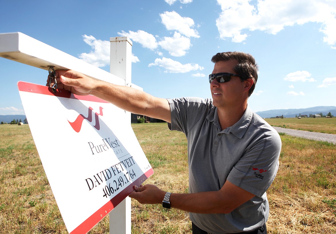 PureWest broker David Fetveit adjusts a sign at a property on Manning Road in Kalispell on July 20. (Mackenzie Reiss/Daily Inter Lake)