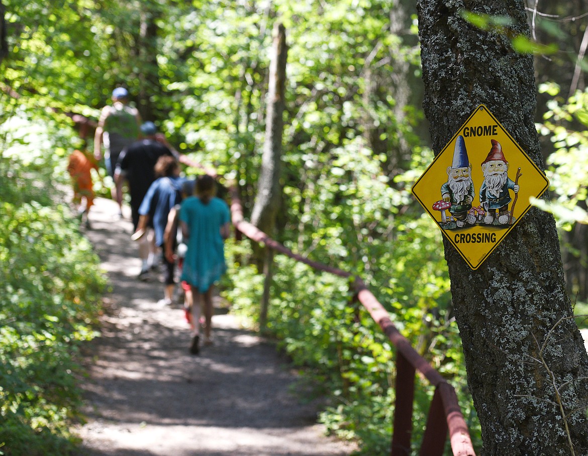 A gnome crossing sign hangs in a tree as a tour group explores the House of Mystery in Columbia Falls.