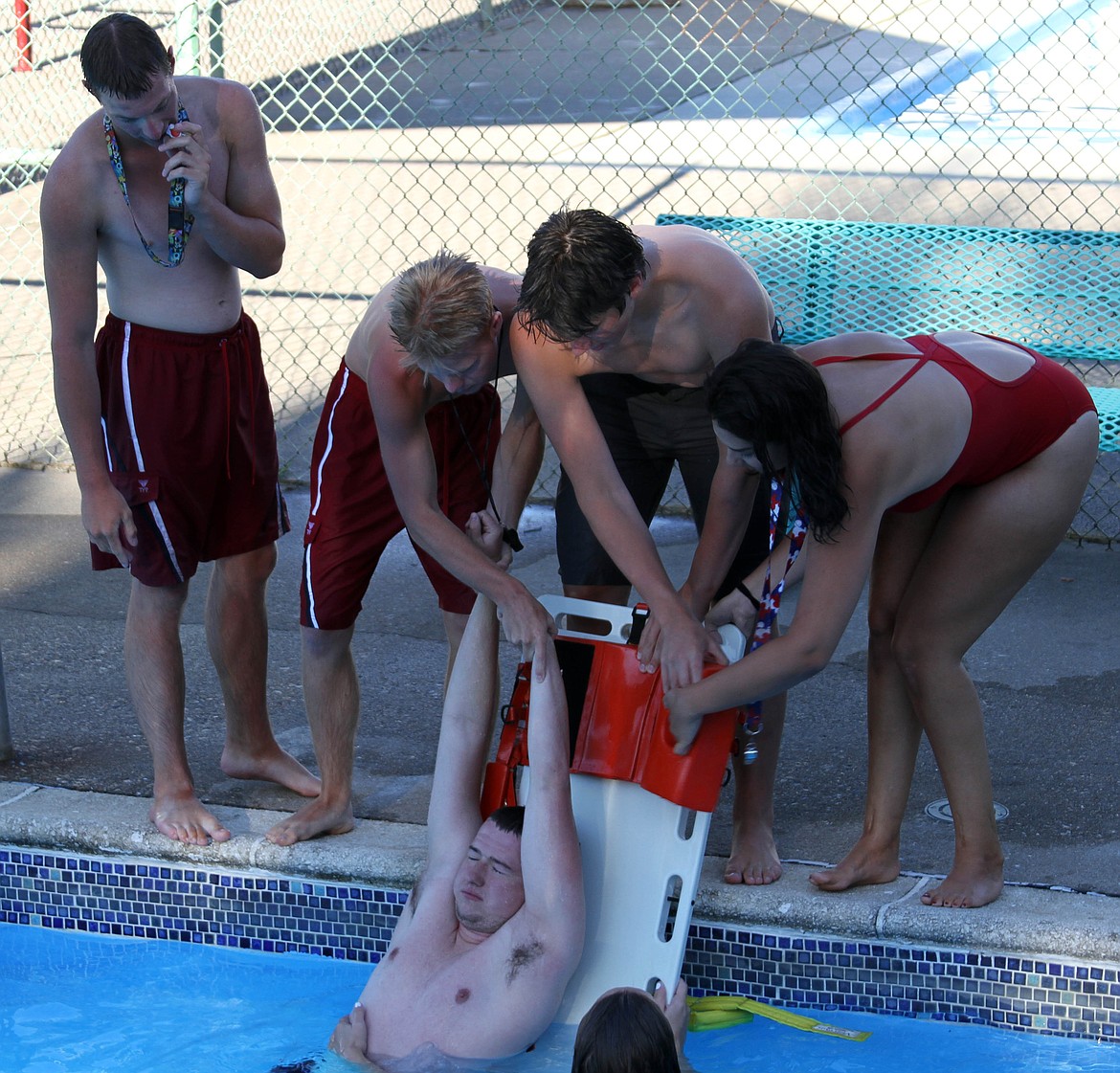 Lifeguards at the Kellogg Pool work to get a drowning victim on their new backboard during an inservice simulation earlier this week.