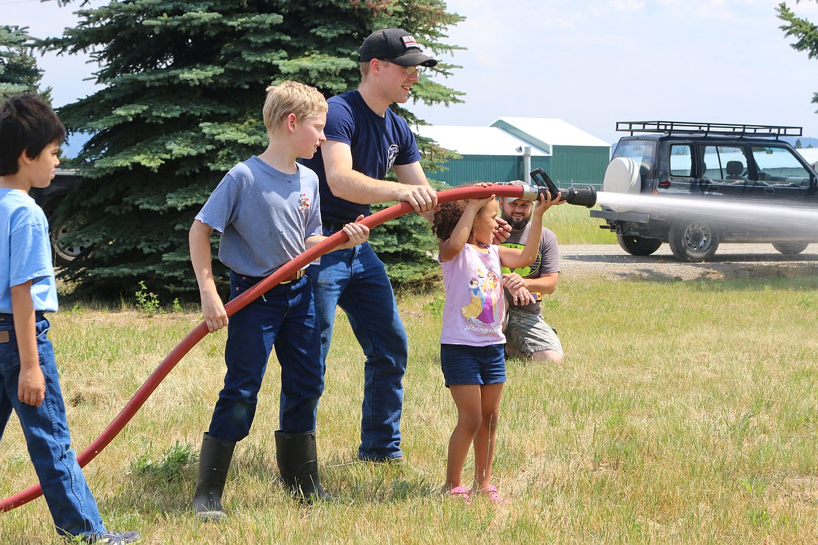 Photo by Mandi Bateman
Teamwork knows no age &#151; North Bench Volunteer Firefighter Granite Allinger teaches children how to use a fire hose at Saturday&#146;s 40th anniversary celebration.